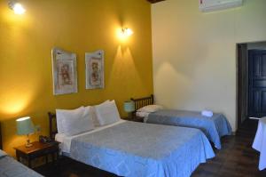 um quarto com 2 camas e uma parede amarela em Hotel Fazenda Villa-Forte em Engenheiro Passos