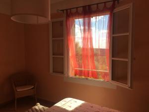 1 dormitorio con ventana y cortina roja en La Ferme du petit Ségriès Bed and Breakfast, en Moustiers-Sainte-Marie