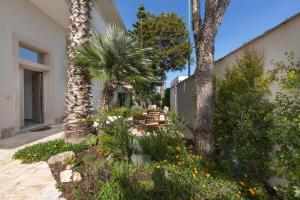 a patio with a palm tree and a table and chairs at B&B Le Radici del Salento Luxury Rooms in San Pancrazio Salentino