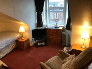 Schlafzimmer mit einem Bett, einem TV und einem Stuhl in der Unterkunft Glades House in Glasgow