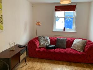 um sofá vermelho numa sala de estar com uma janela em Central Townhouse & Terrace em Brighton & Hove