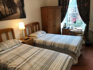 2 Betten in einem Hotelzimmer mit Fenster in der Unterkunft Glades House in Glasgow