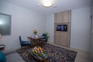 Habitación de hotel con TV, sofá y mesa. en Fortis Hotel Fujairah en Fujairah