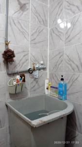 La salle de bains est pourvue d'une baignoire et de carrelage blanc. dans l'établissement Ketupat Palas Homestay, à Kulim