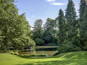 a pond in a park with trees and a green field at Mercure Sheffield Kenwood Hall & Spa in Sheffield