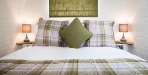 una camera da letto con un letto con cuscini e due lampade di Weedingshall Lodges a Falkirk