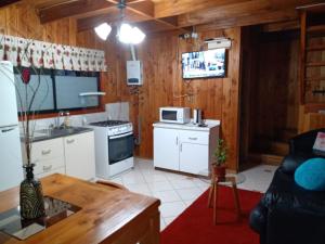 a kitchen with white cabinets and a stove top oven at CABAÑA INTERIOR VILLARRICA in Villarrica