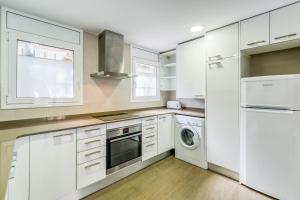 a kitchen with white cabinets and a washer and dryer at Hauzify I Apartament Edelweiss in Platja  d'Aro