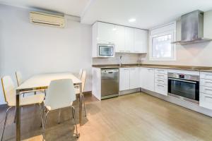 a kitchen with white cabinets and a table and chairs at Hauzify I Apartament Edelweiss in Platja  d'Aro