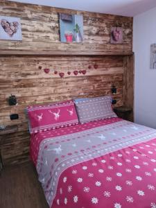 1 dormitorio con cama rosa y pared de madera en Appartamento Gentiana psdCIR0037 en Pré-Saint-Didier