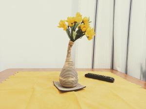 a vase with yellow flowers on a table with a remote at Kwatery w Gołdapi in Gołdap