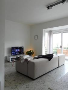 a white living room with a couch and a tv at Fleuri Westende in Middelkerke