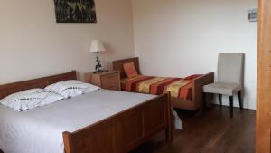 a bedroom with a bed and a chair in it at appartement "les goumis" in Baccarat