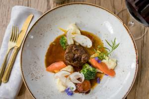 a plate of food with meat and vegetables on a table at Hotel und Alpen Apartments mit Sauna - Bürglhöh in Bischofshofen