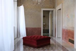 un soggiorno con ottomana rossa in una camera di Palazzo Albricci Peregrini a Como
