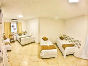 a hotel room with two beds and a table at Pousada Sereia do Porto in Porto De Galinhas