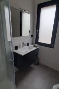 un bagno con un lavandino, uno specchio e una finestra di B&B Juniperus a SantʼAnna Arresi