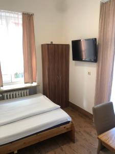 a bedroom with a bed and a tv on the wall at Hotel Pension Schmellergarten in Munich