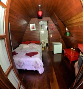 1 dormitorio con 1 cama en una habitación de madera en Pousada Perola da Mantiqueira en Monte Verde