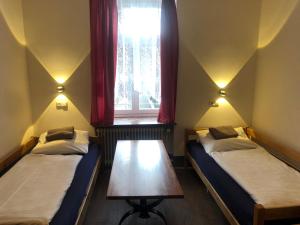 ミュンヘンにあるホテル ペンション シュメラーガルテンの窓とテーブル付きの部屋のベッド2台