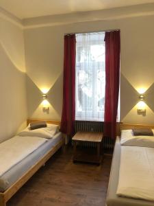 two beds in a room with a window and red curtains at Hotel Pension Schmellergarten in Munich
