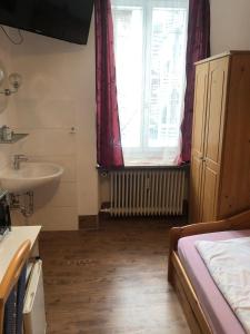 a bathroom with a bed and a sink and a window at Hotel Pension Schmellergarten in Munich