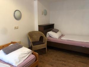 a room with two beds and a chair and a mirror at Hotel Pension Schmellergarten in Munich