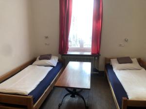two beds in a room with a table and a window at Hotel Pension Schmellergarten in Munich