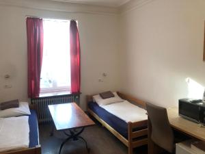 a room with two beds and a desk and a window at Hotel Pension Schmellergarten in Munich