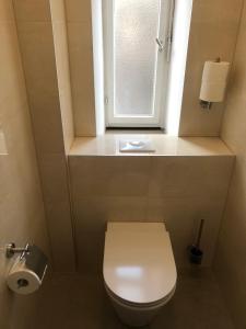 a bathroom with a white toilet and a window at Hotel Pension Schmellergarten in Munich