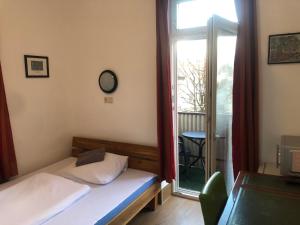 a small bedroom with a bed and a window at Hotel Pension Schmellergarten in Munich