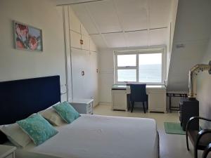 1 dormitorio con cama, escritorio y ventana en Rachawadee Accomodation​ & Health Spa, en Simonʼs Town