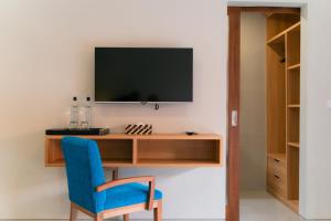 escritorio con silla azul y TV en la pared en The Ume, en Canggu