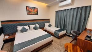 a hotel room with two beds and a desk at Suvin Residency with Rooftop Swimming Pool in Udaipur