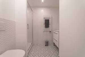 La salle de bains blanche est pourvue d'une douche et de toilettes. dans l'établissement apparthotel-gare-chambery, à Chambéry