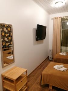 a room with two beds and a tv on the wall at Guesthouse Carl Schmidt in Põltsamaa