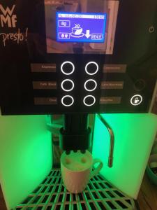 فندق بنسيون شميلارغارتن في ميونخ: آلة القهوة مع كوب من القهوة على رف