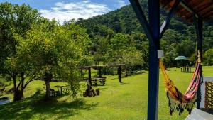 uma rede num parque com mesas de piquenique e árvores em Hotel Fazenda Pedra Grande em Visconde de Mauá
