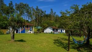 a yard with a house and a hammock in the grass at Hotel Fazenda Pedra Grande in Visconde De Maua