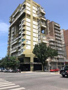 un edificio alto amarillo en una calle de la ciudad con un árbol en Bubuhouse estadía mínima dos noches en Rosario