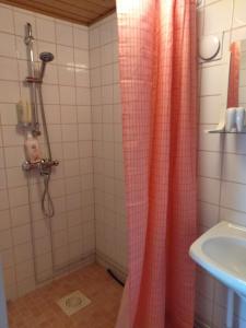 una ducha con cortina de ducha rosa junto a un lavabo en Art House & Sculpture Garden, en Mänttä