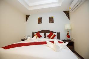 Un dormitorio con una cama blanca con almohadas rojas y blancas. en Chang Siam Inn, en Bangkok