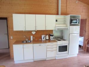 La cuisine est équipée de placards blancs et d'un four avec plaques de cuisson. dans l'établissement Hummingen Camping hus 2, à Dannemare