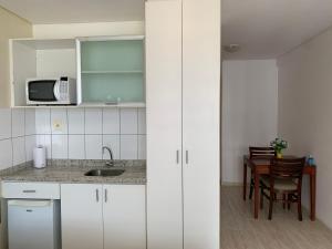 a kitchen with white cabinets and a table with a microwave at Flat Athenas 1402 in Salvador