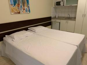 a white bed with two pillows in a room at Flat Athenas 1402 in Salvador