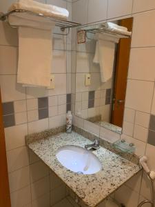 a bathroom with a sink and a mirror and towels at Flat Athenas 1402 in Salvador +12 photos