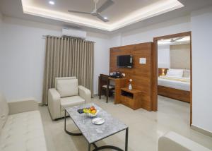 ein Wohnzimmer mit einem Sofa, einem Tisch und einem Bett in der Unterkunft Hotel Laxmi Cityside in Mangaluru