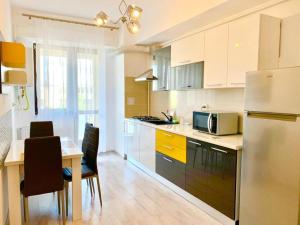 uma cozinha com um frigorífico e uma mesa com cadeiras em Karina New Flat near Palas Mall em Iaşi