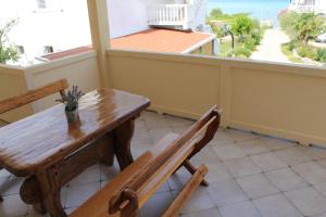 a wooden table and bench on a balcony with a view of the ocean at Apartments Kampor Damira in Rab