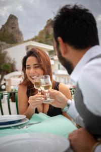 a man and woman sitting at a table with a glass of wine at Bellevue del Golfo Hotel & Spa in Sferracavallo